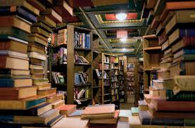a picture of a window but it's made of books and through the hole in the book wall you can see more books